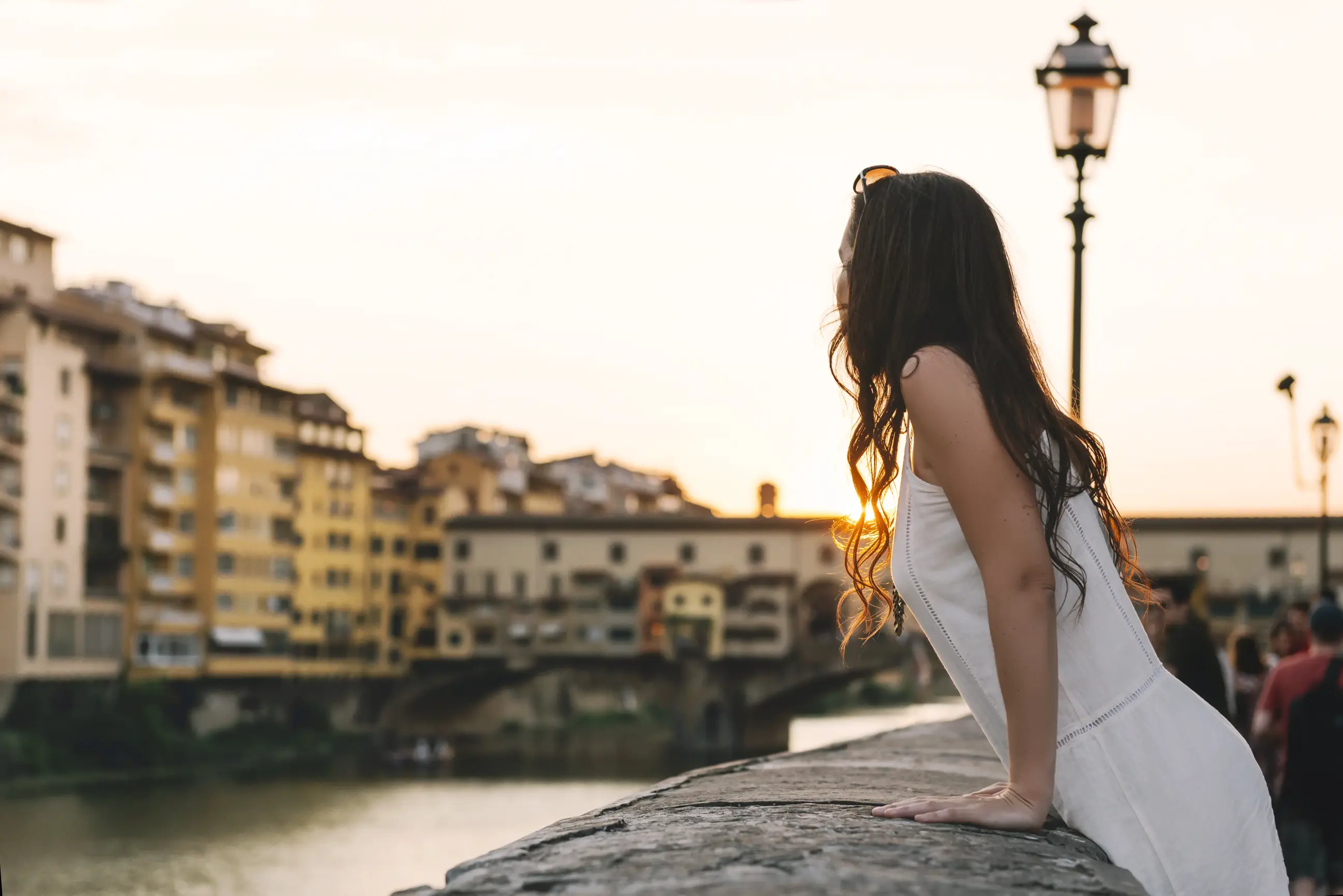 day-hero-woman-watching-sunset-behind-ponte-vecchio-florence-italy.webp