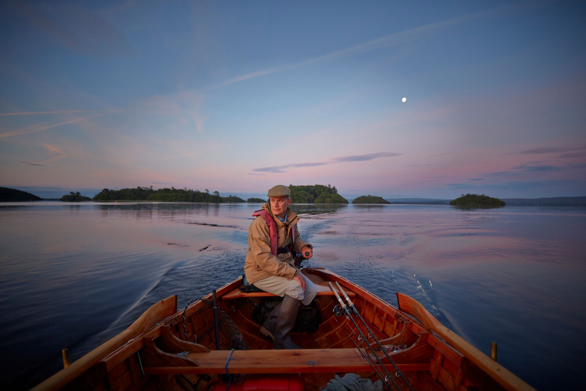 Man driving a boat during a dusk fishing trip at Ashford Castle in Ireland