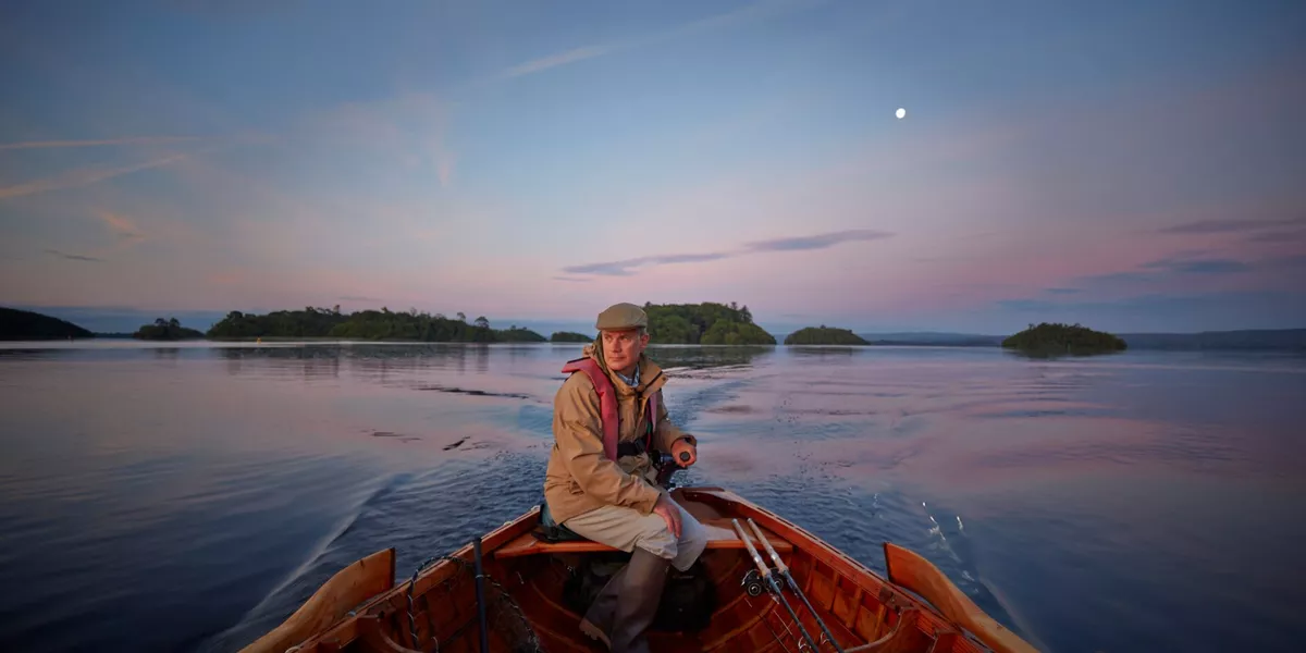 Man driving a boat during a dusk fishing trip at Ashford Castle in Ireland