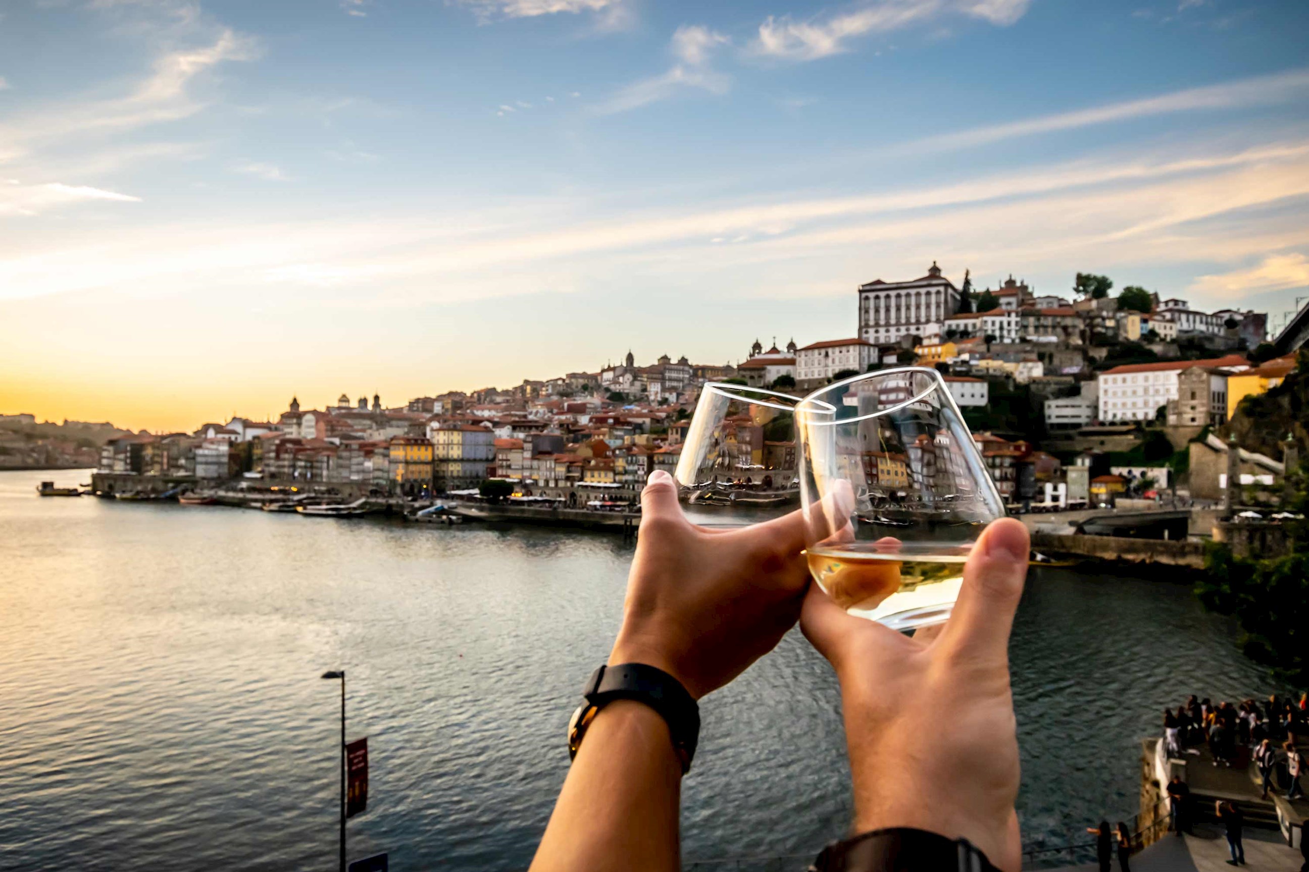 Two glasses toasting in front of a city view of Douro, Portugal 