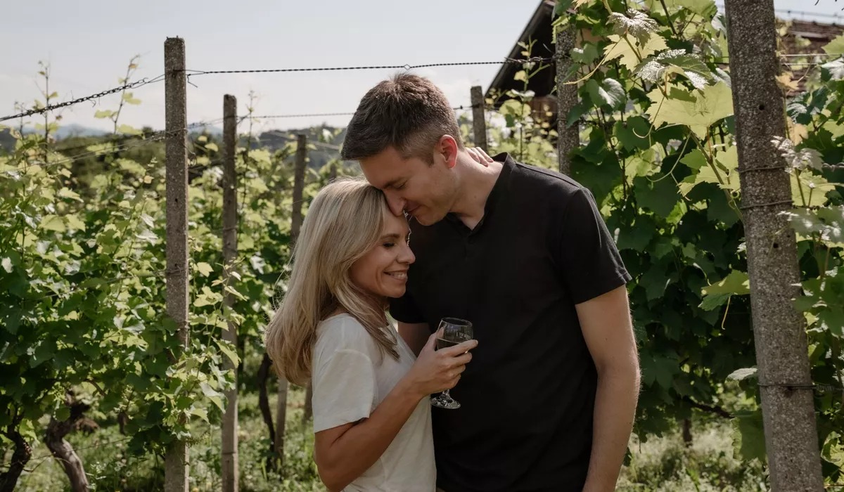 Couple drinking wine and hugging in the vineyard