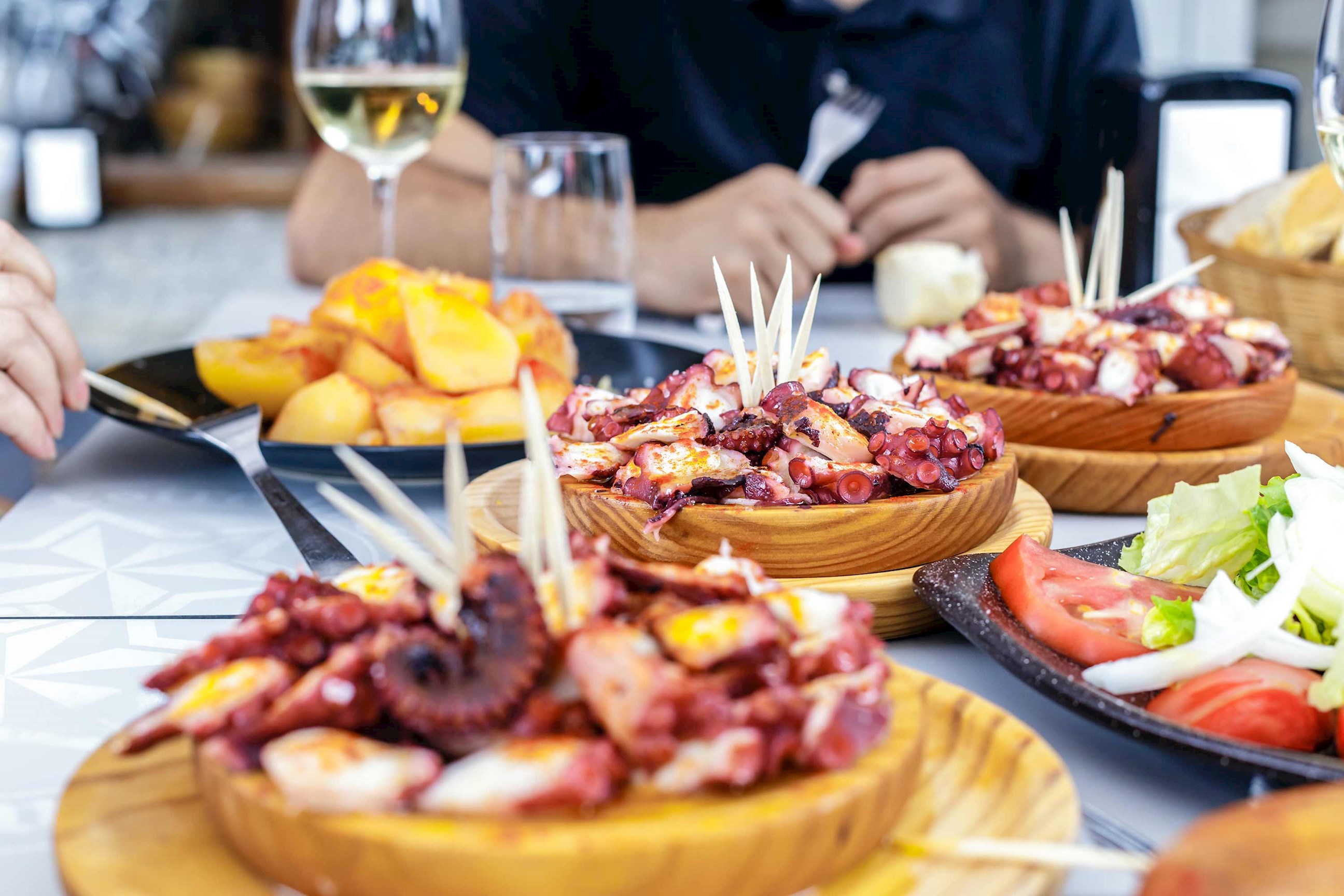 Close-up of pulpo a la gallega served on wooden plates with boiled potatoes