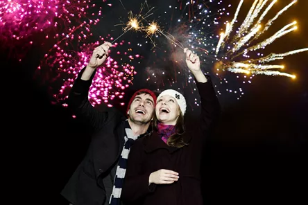 Couple Holding Sparklers At Firework Display