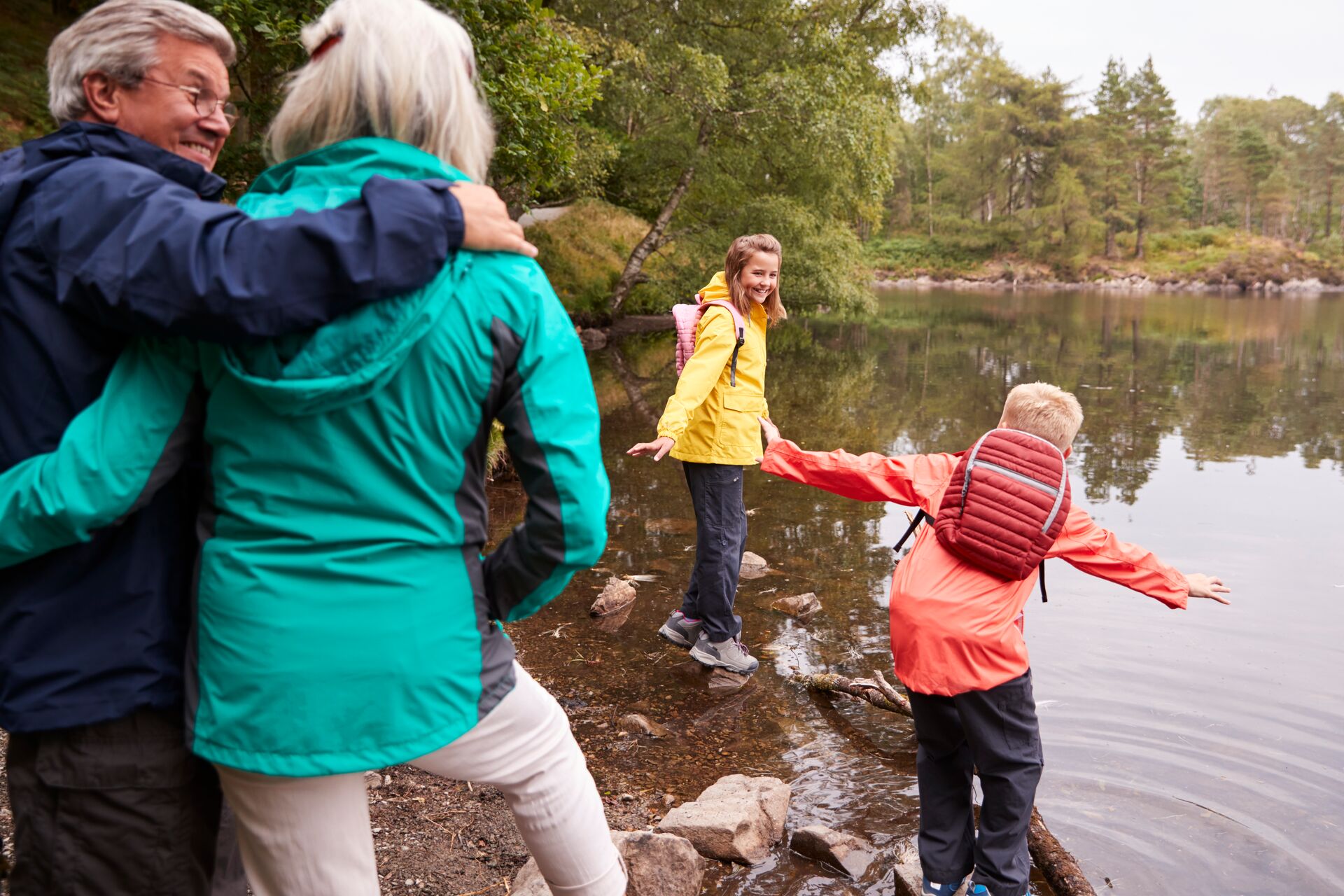 Two children playing in a lake with their grandparents in the foreground
