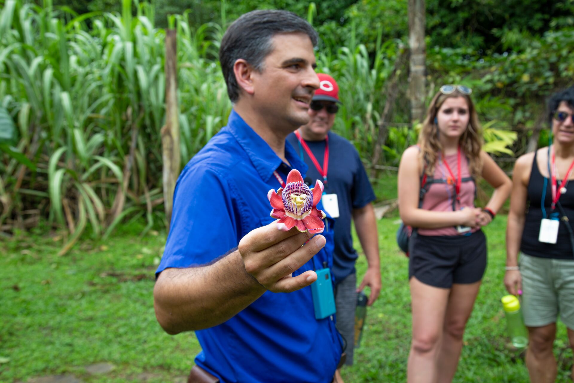 Be My Guest Host holding a flower in the rainforest