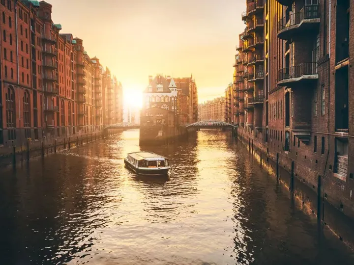 Canal amidst buildings in city during sunset
