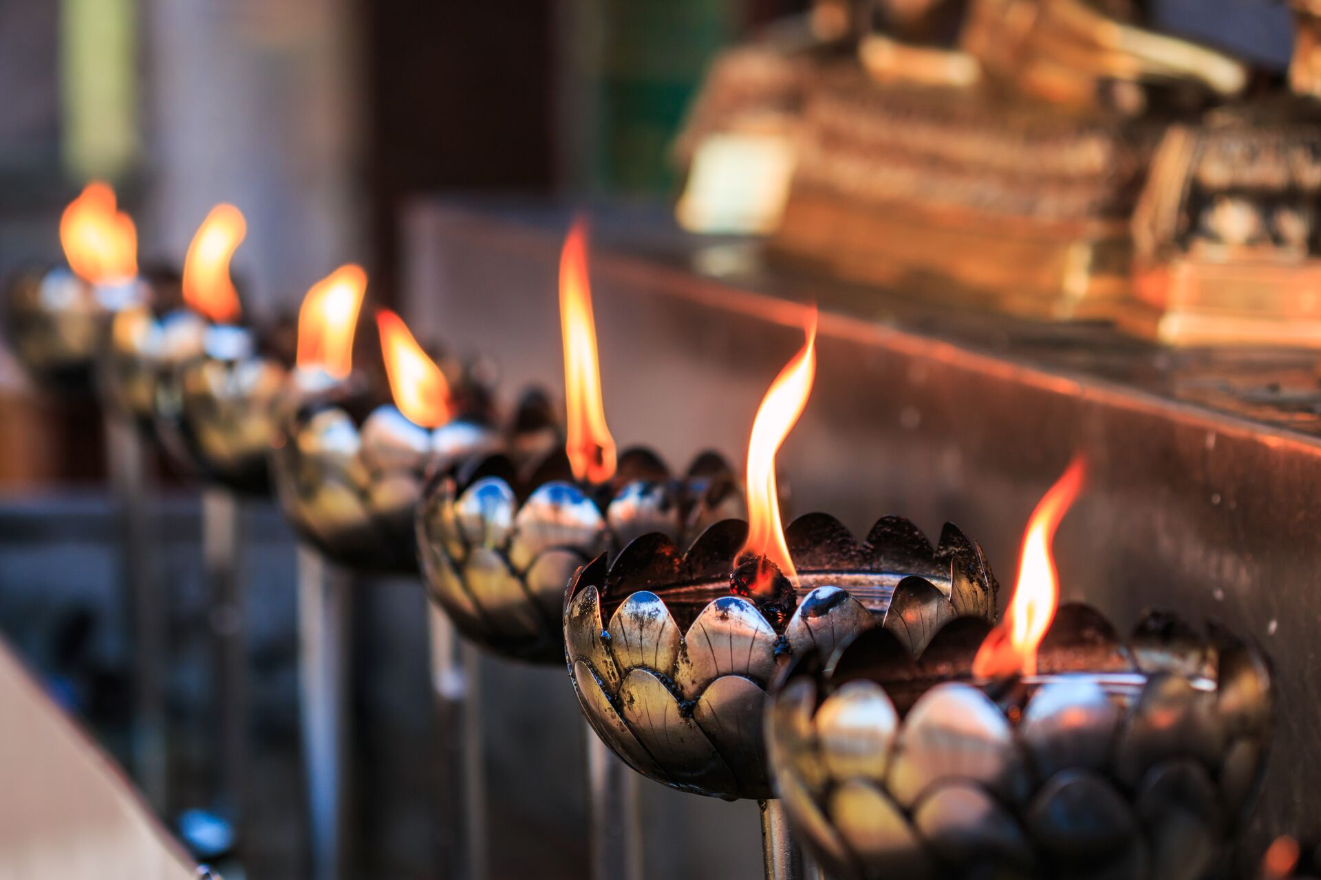 Oil lamps arranged in front of a statue in a temple