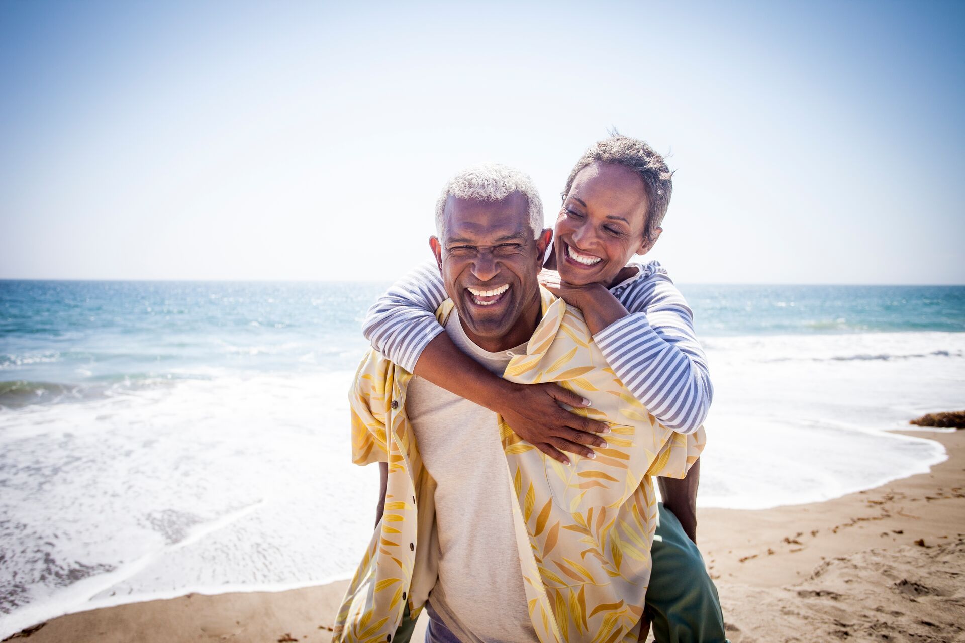 Couple piggyback on beach in USA