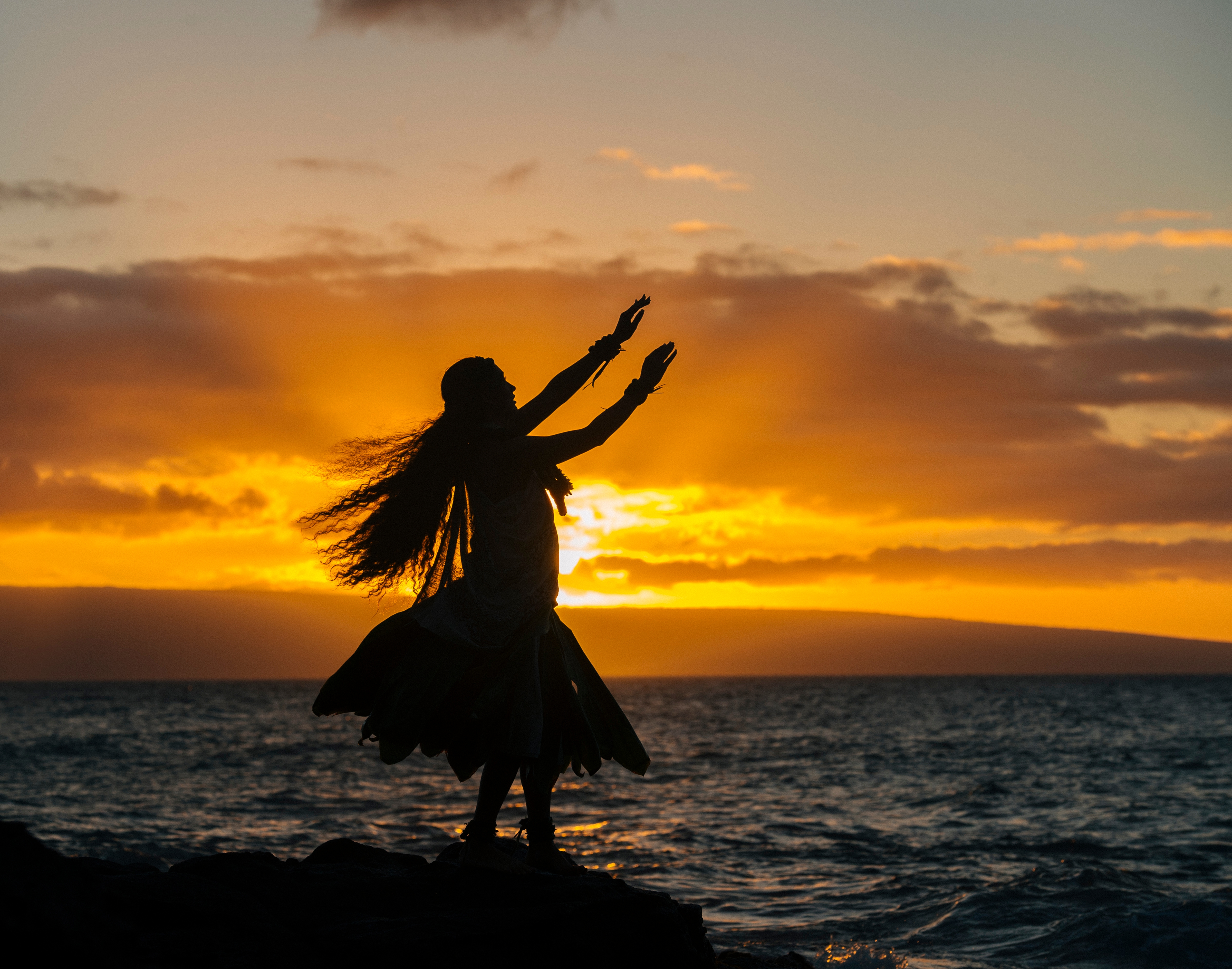 A woman Hula Dancing On Coastal Rock At Sunset, Maui, Hawaii, USA