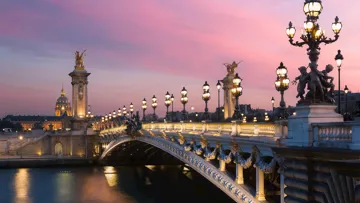 An evening view of the Pont Alexandre III Bridge in Paris, France