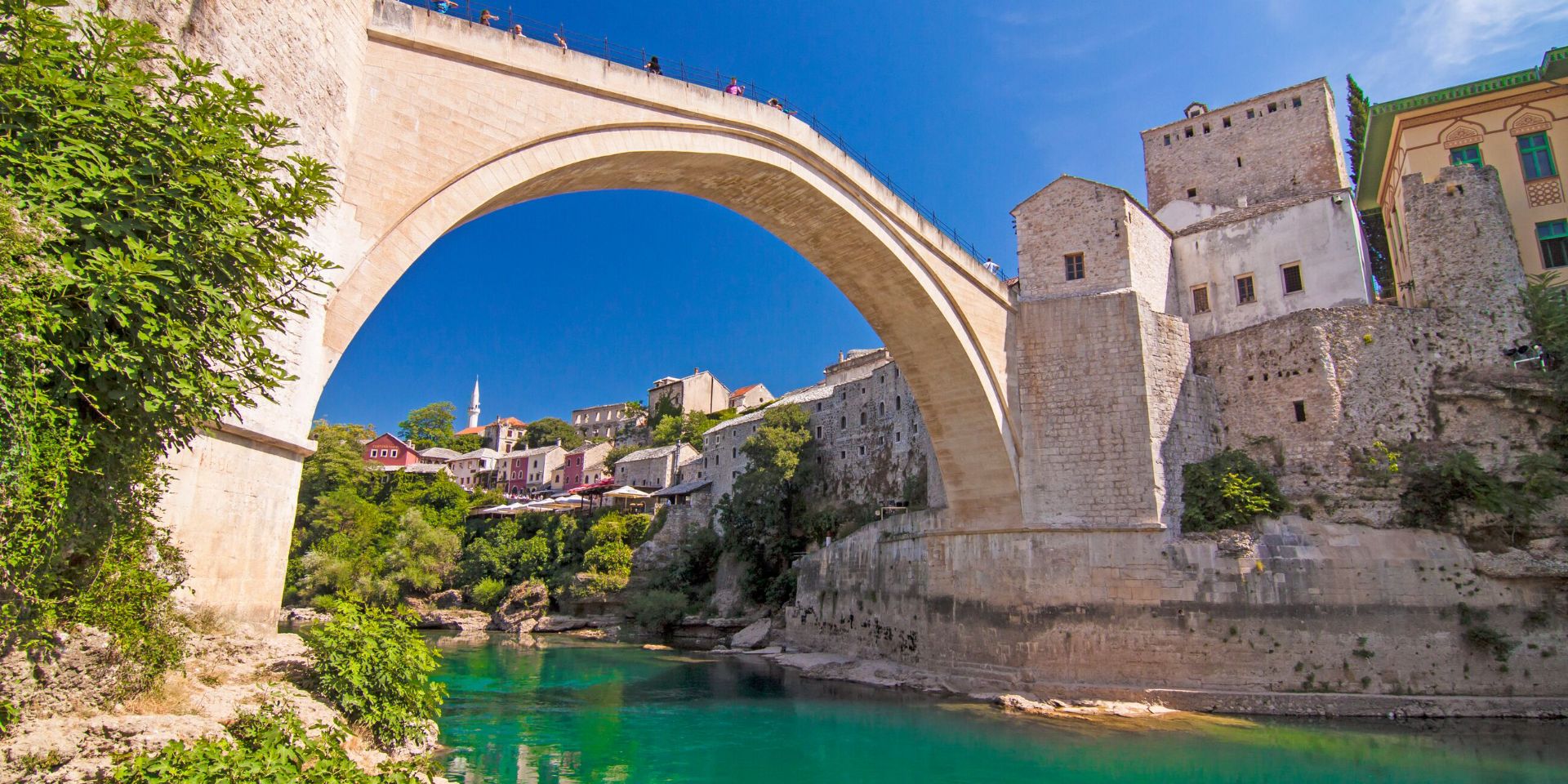 A stone bridge over a river with buildings on the other side