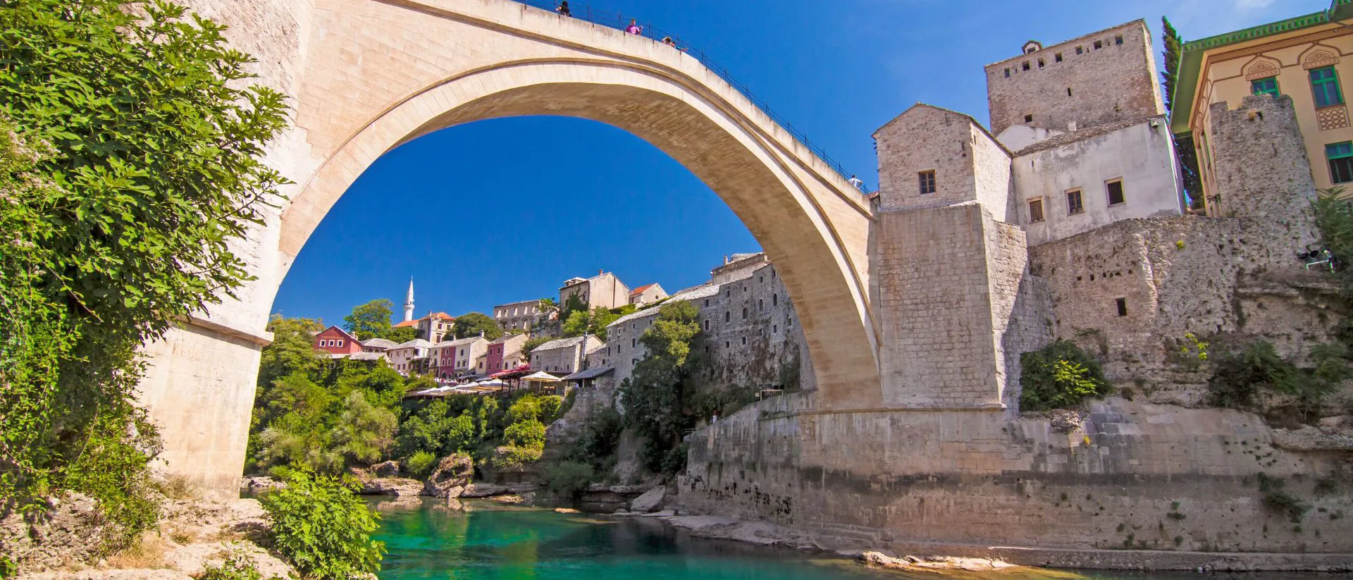 A stone bridge over a river with buildings on the other side