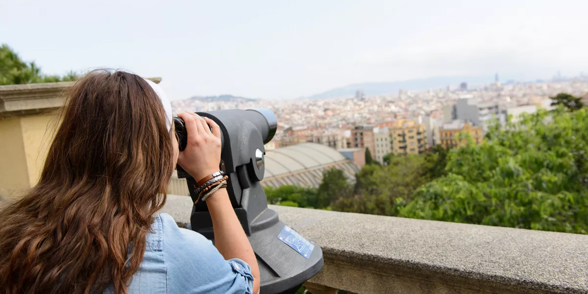 Woman looking at the city through a telescope