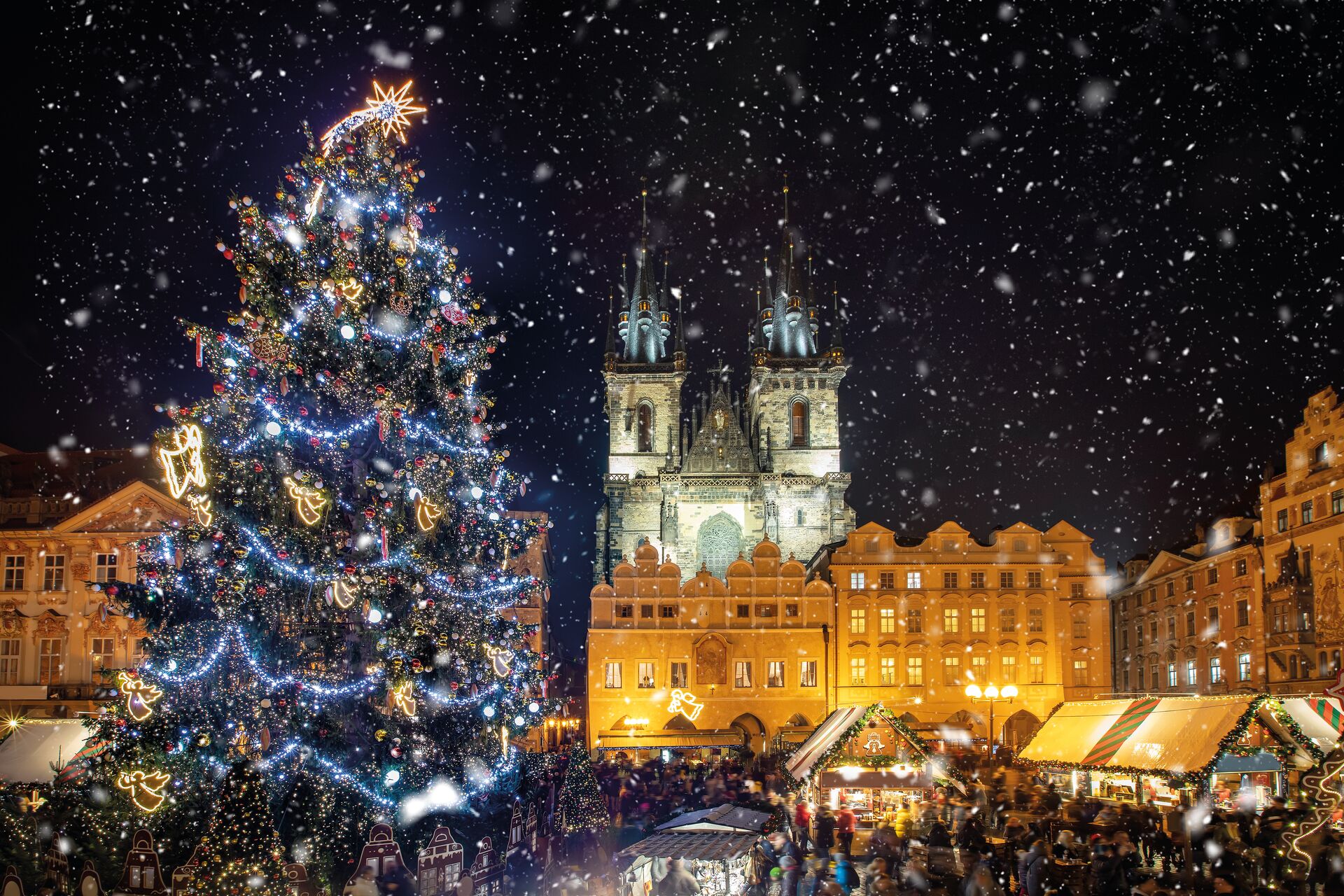 Low Angle View Of Decorated Christmas Tree And Tyn Church Against Sky During Snowfall At Nigh