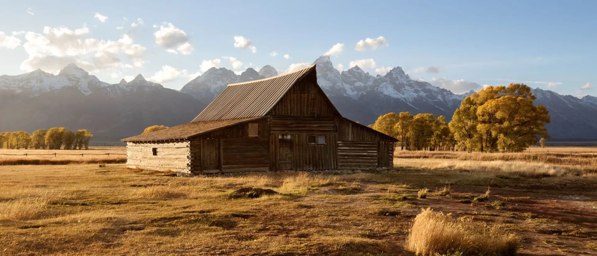 A barn in a field with mountains in the background in Grand Teton National Park, Wyoming