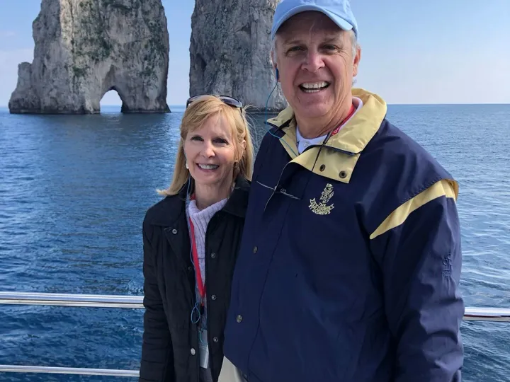 Roxanne Foster standing on a boat with Tour Director nearby rocks close to Isle of Capr