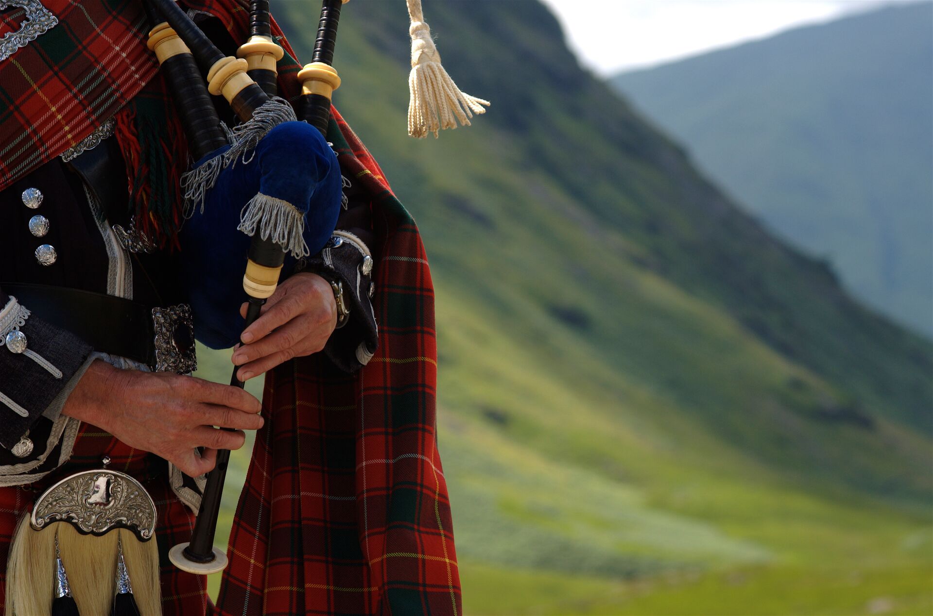 Bagpiper In Scotland with the Highlands behind him