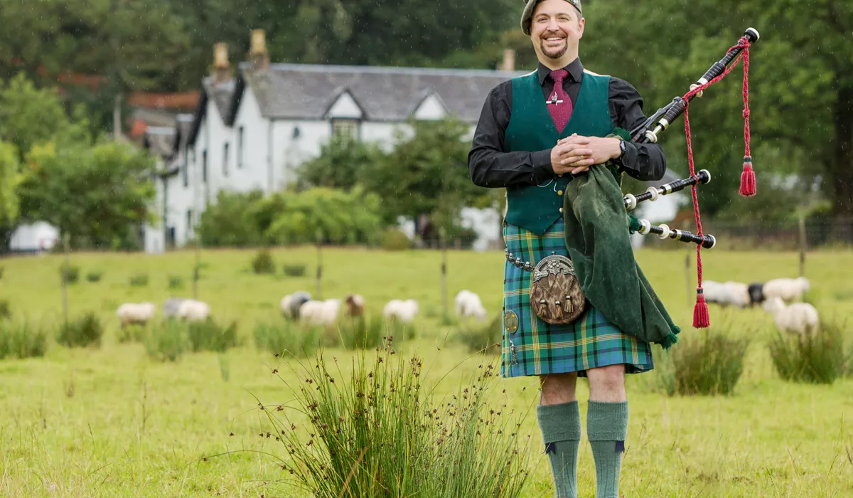A bagpipe player standing on a field, Scotland