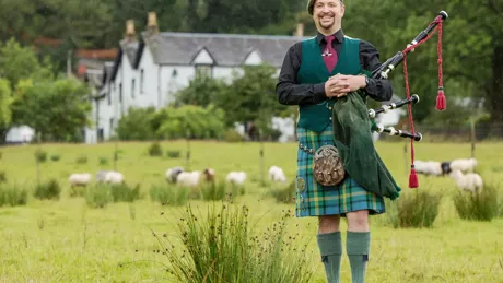 A bagpipe player standing on a field, Scotland