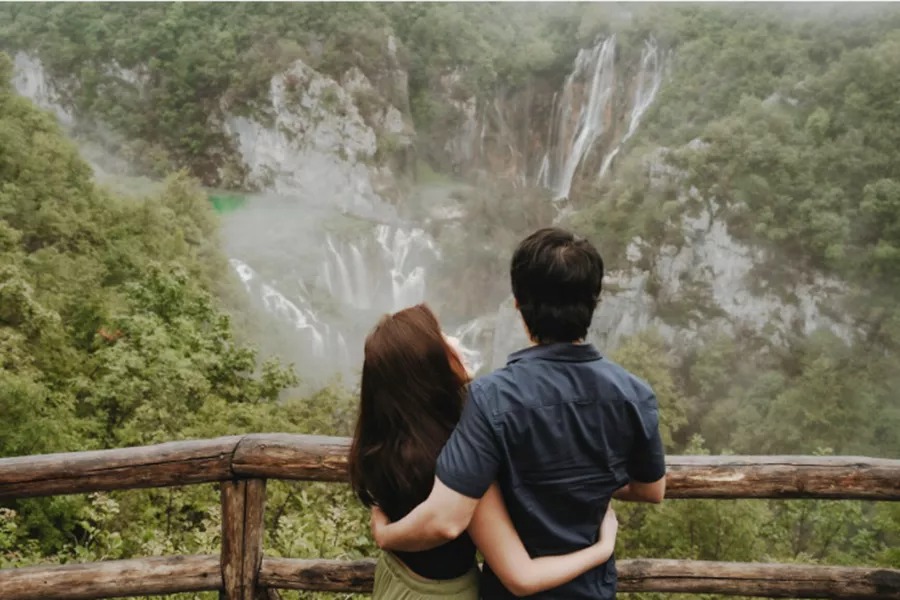 Couple watching the waterfalls from the wooden bridge