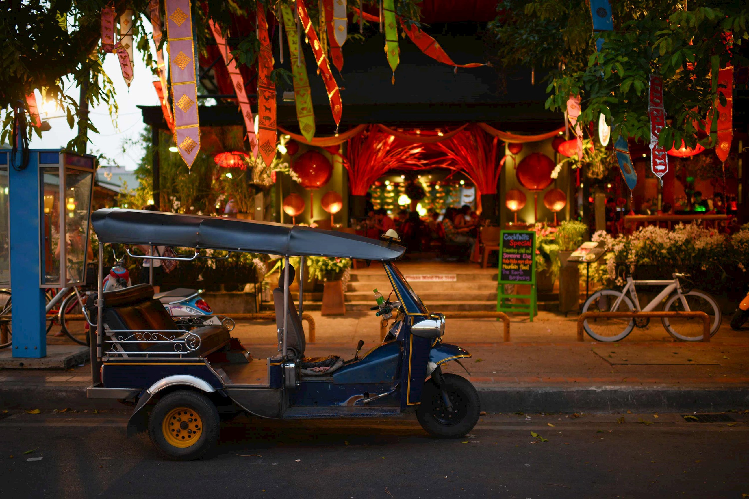 Tuk-tuk parked outside restaurant decorated with lanterns