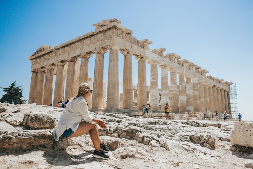 Woman relaxing while looking at Parthenon Temple against clear sky 
