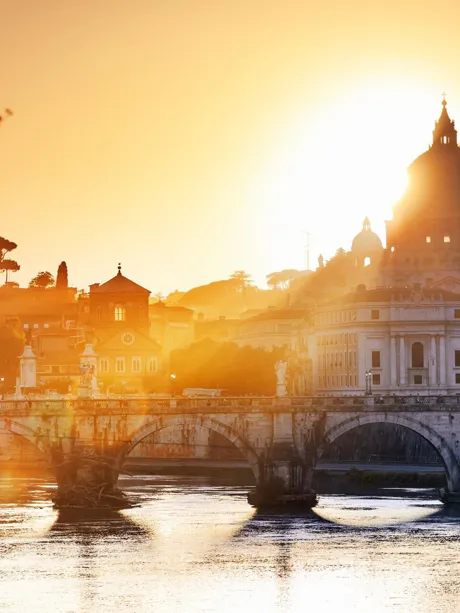 St. Peter Basilica and old bridge over river at sunset in Rome, Italy