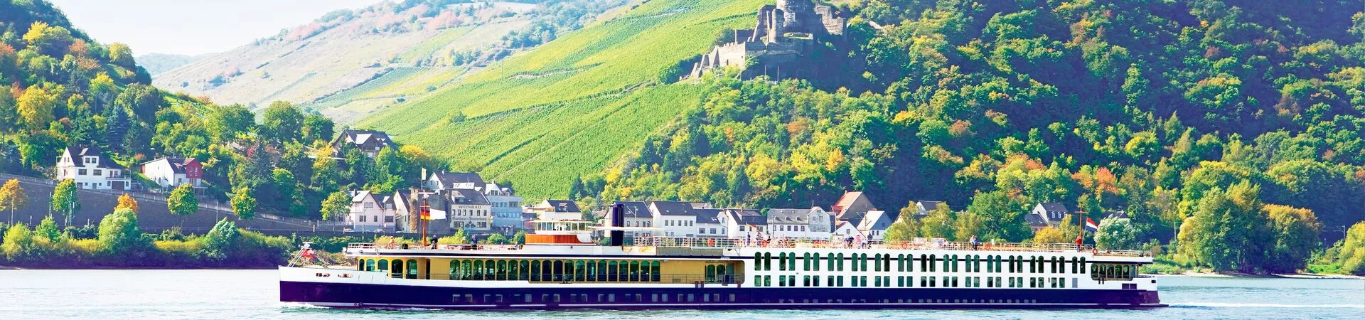 The Trafalgar river cruise ship, Verity, sailing on the Rhine with a castle on the shoreline beyond.