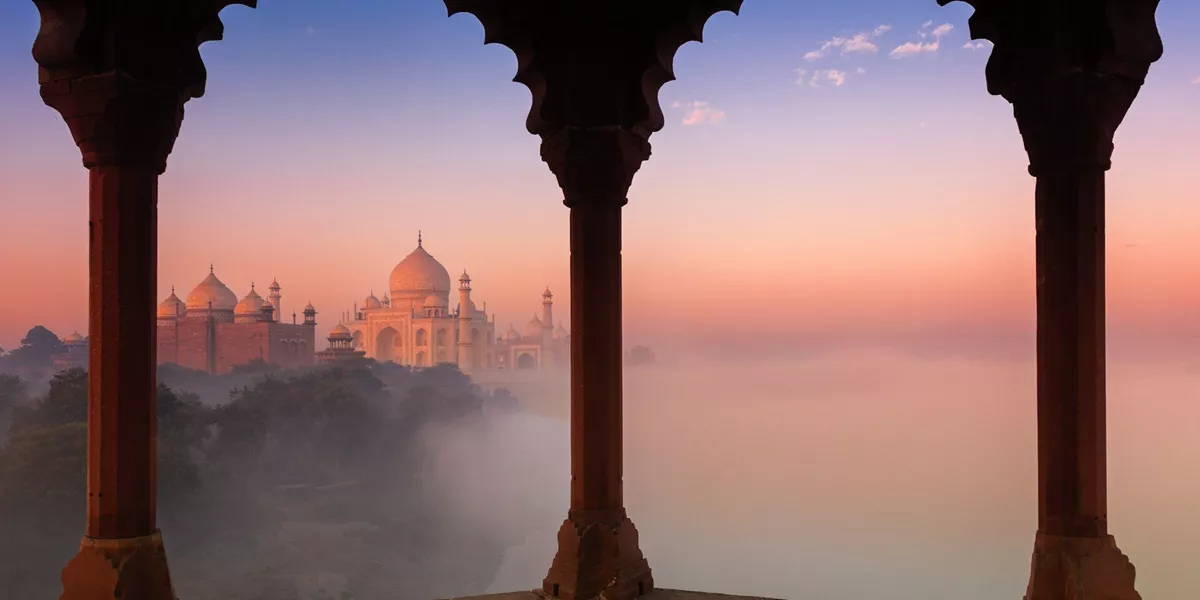 Taj Mahal in India partly obscured by fog framed by arches