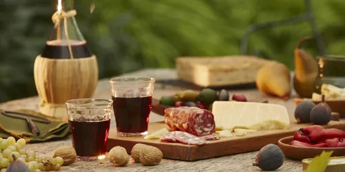 Wine, local cheeses and meats spread on a wooden table in Italy