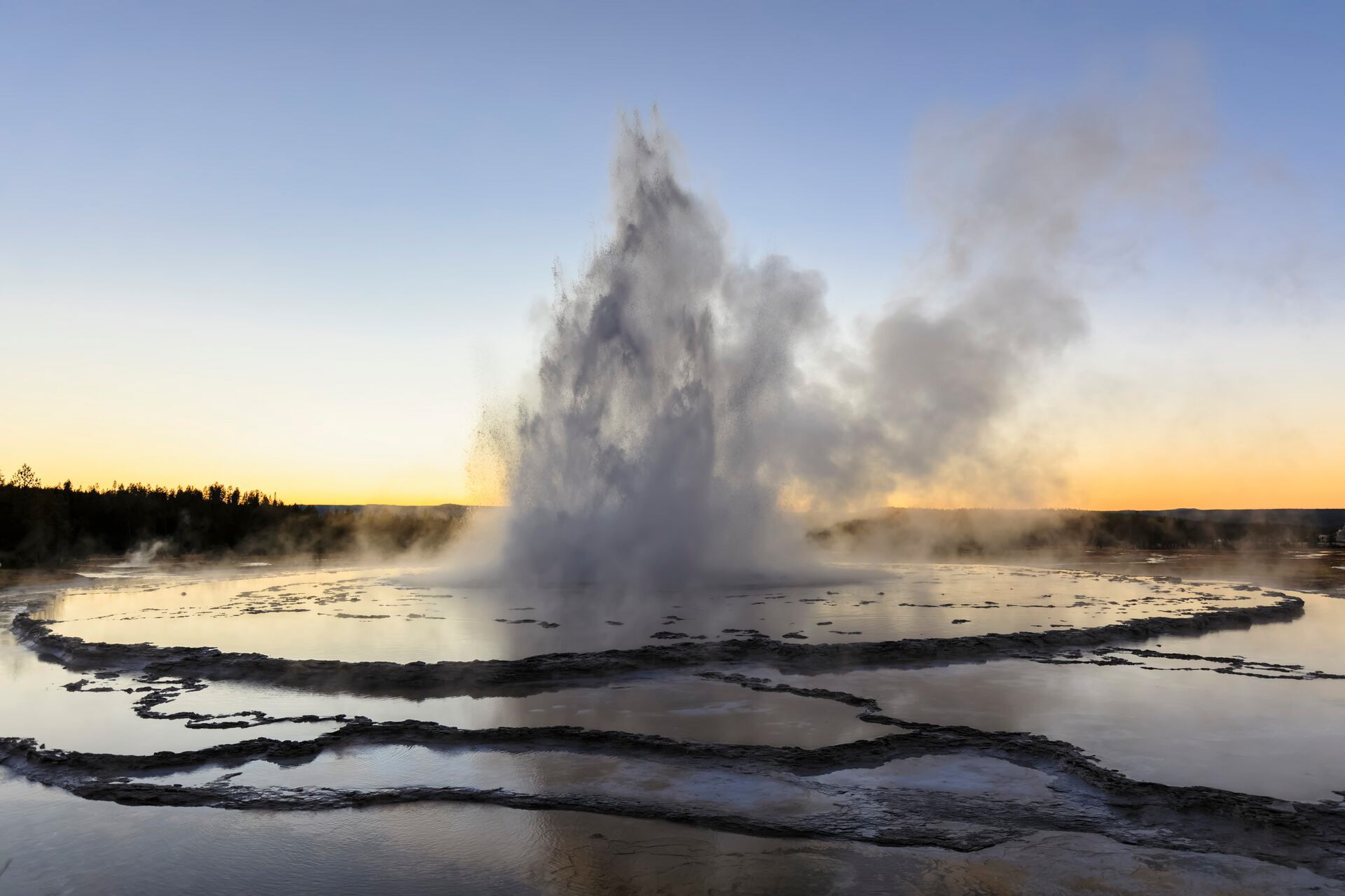 A geyser spewing water into the air at sunset in USA, Wyoming, Yellowstone National Park