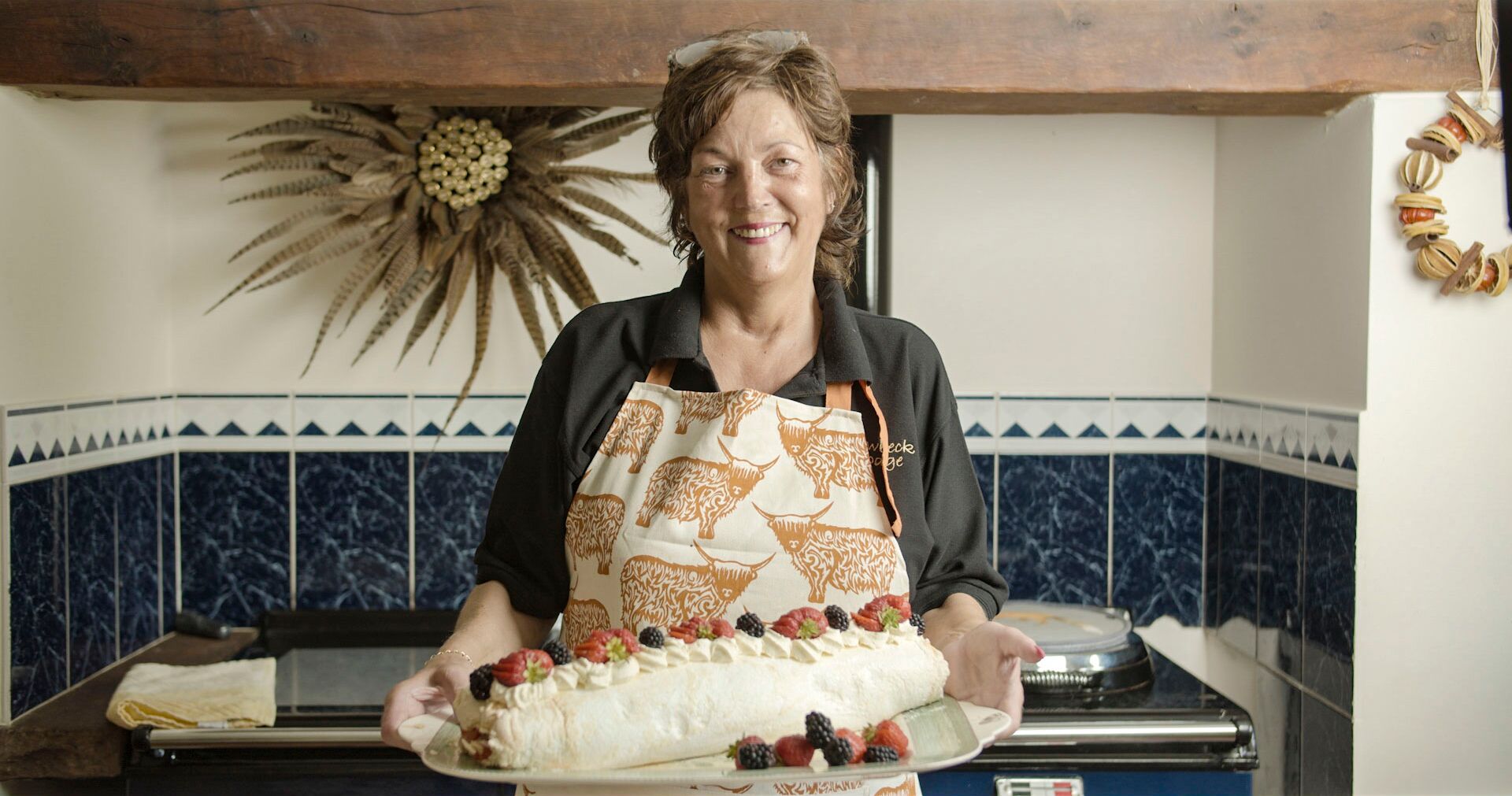 Anne Stobart holding a traditional dessert in her Lodge in Cumbria, England