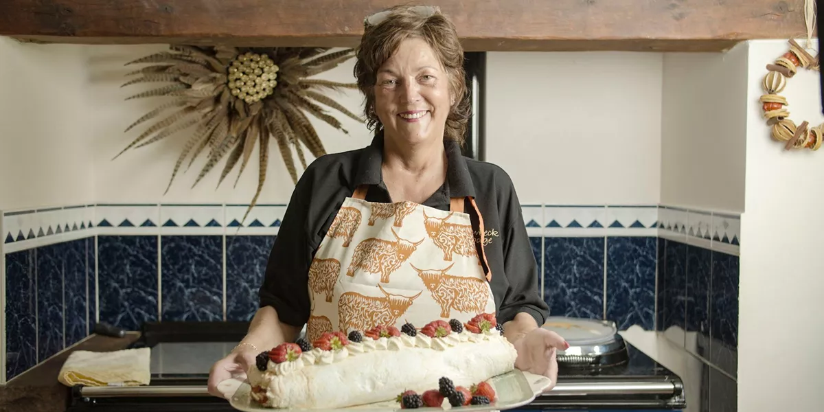 Anne Stobart holding a traditional dessert in her Lodge in Cumbria, England