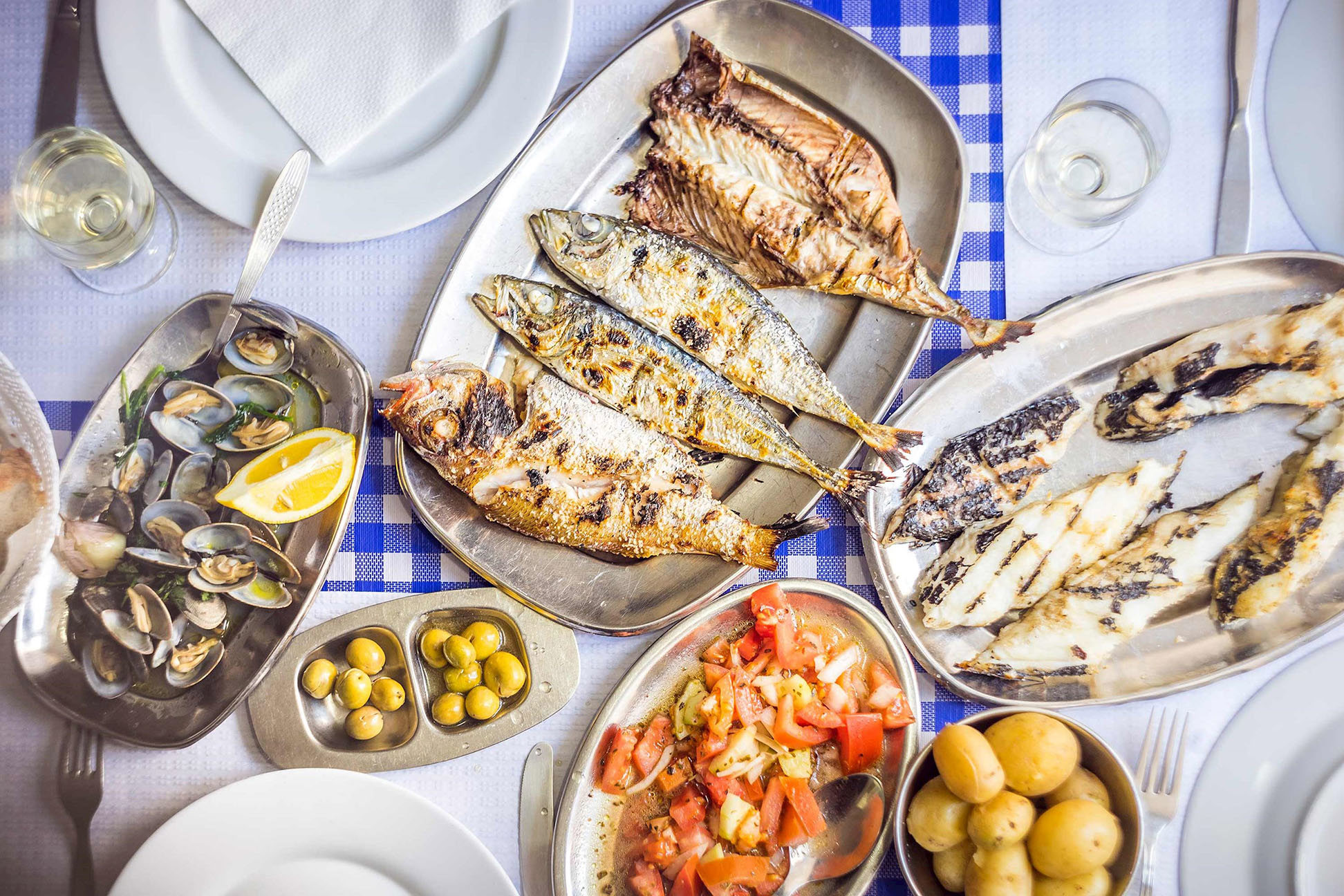 A Portuguese seafood dinner spread including fish, mussels, and vegetables