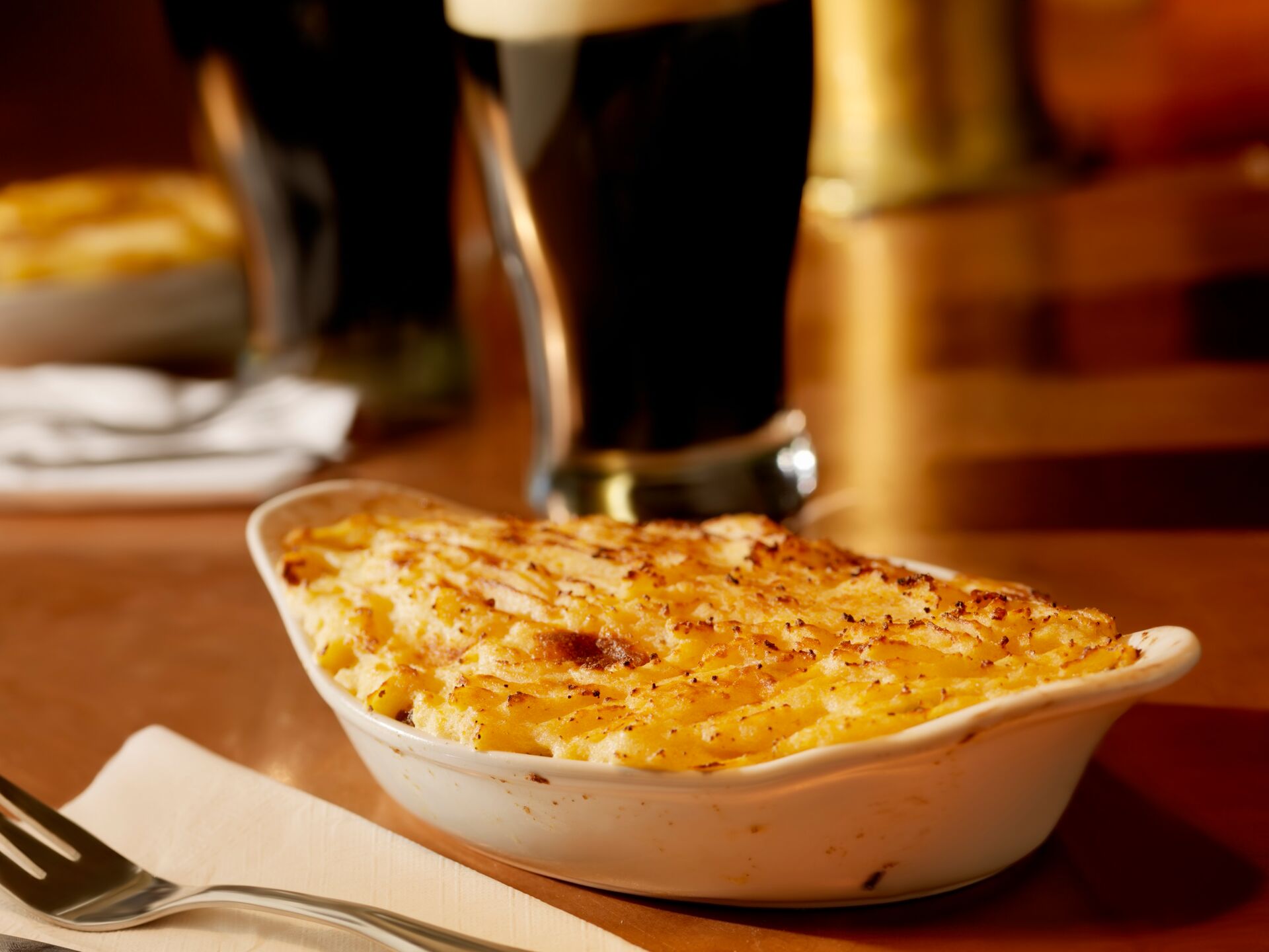 Shepherds pie with pints of stout in the background in an Irish pub in Ireland