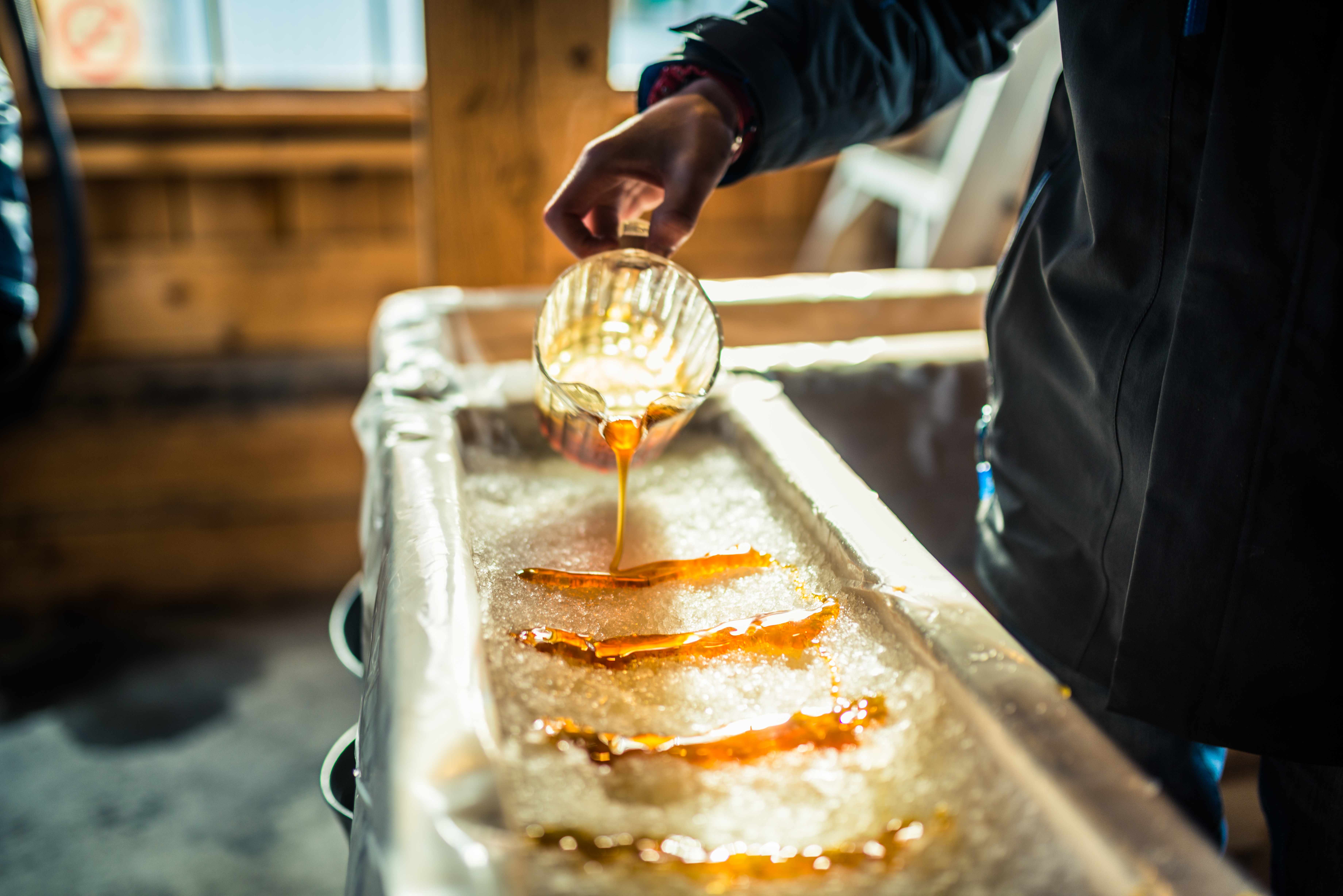 Person Pouring Maple Syrup Onto Snow At Sugar Shack 925426372