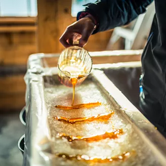 Person Pouring Maple Syrup Onto Snow At Sugar Shack 925426372