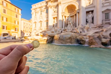 20 cent piece being held up in front of the Trevi Fountain in Rome, Italy