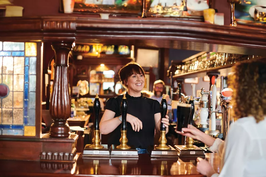 Woman greeting patrons at a pub