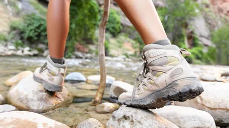 Legs of a hiker crossing mountain stream