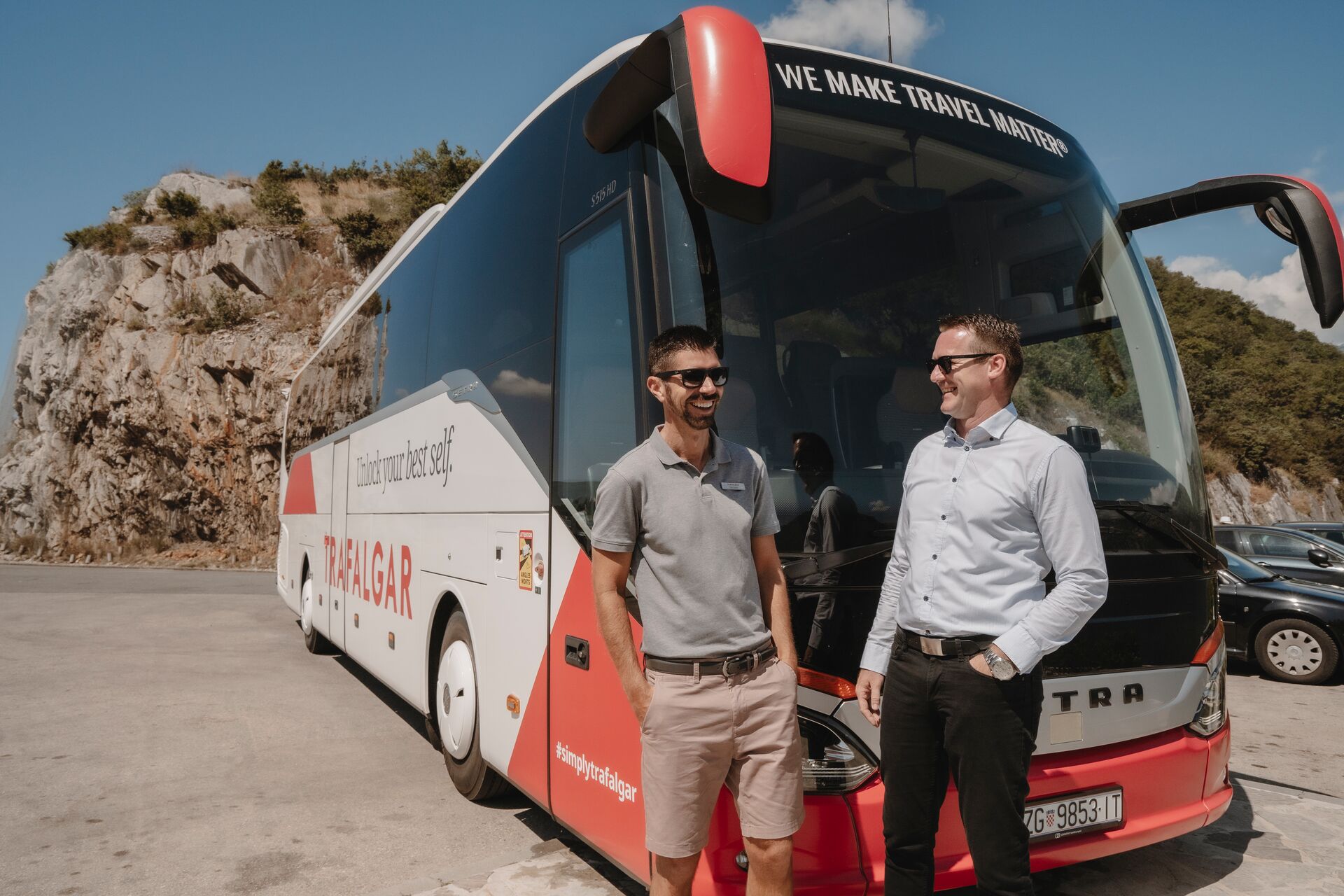 Two men stood next to a Trafalgar coach