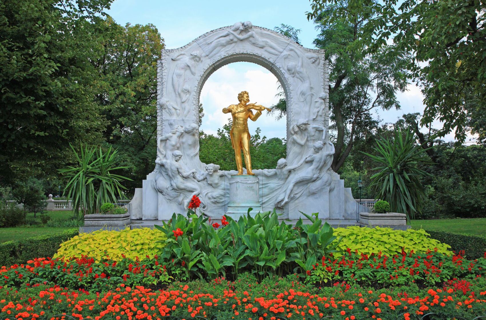 Vienna golden Strauss Monument in park surrounded with flowers and trees, Austria