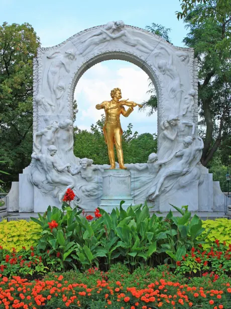 Vienna golden Strauss Monument in park surrounded with flowers and trees, Austria