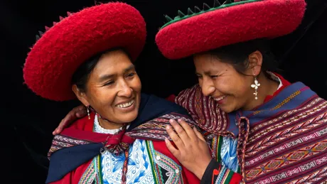 Two Local Women In Colourful Predominantly Red Traditional Local Dress And Hats in Chinchero, Sacred Valley, Peru