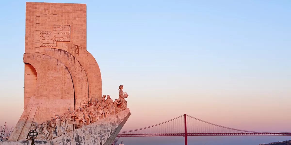The Discoveries Monument with a bridge in the background in Lisbon, Portugal