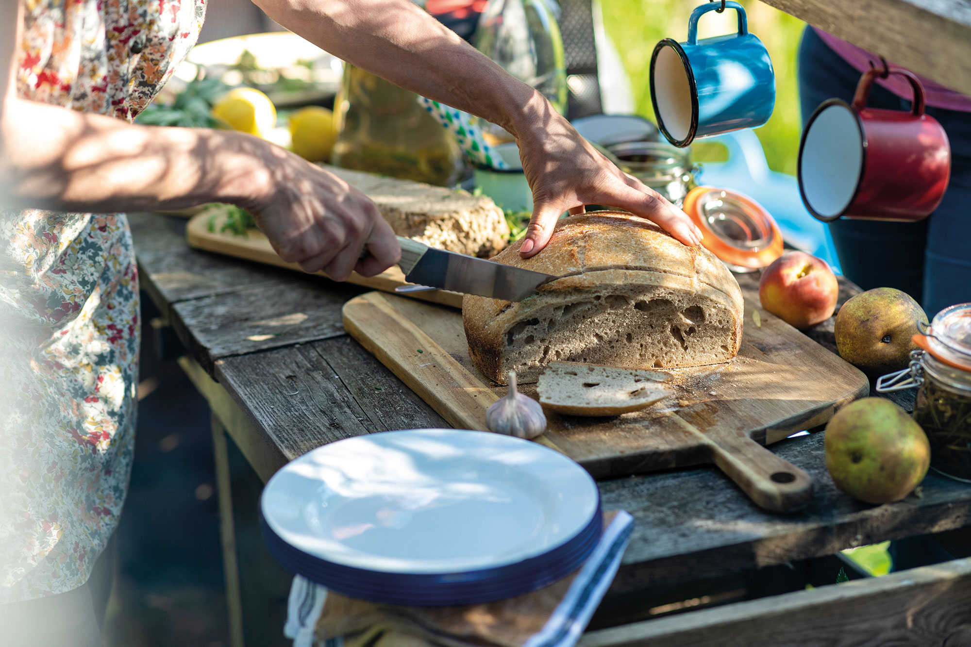 Hands slicing fresh bread on rustic outdoor table setup, Cappadocia, Turkey