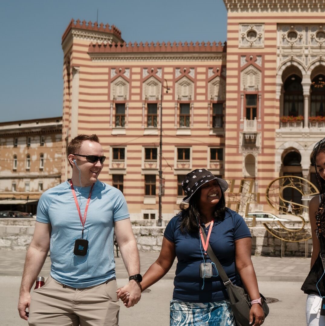 A couple walk hand in hand in front of an elaborate building