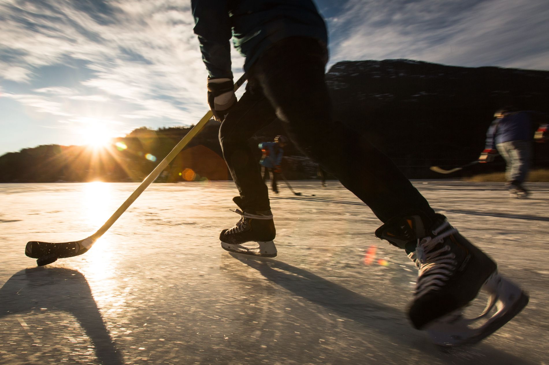 Playing Ice Hockey On Frozen Lake In Sunset