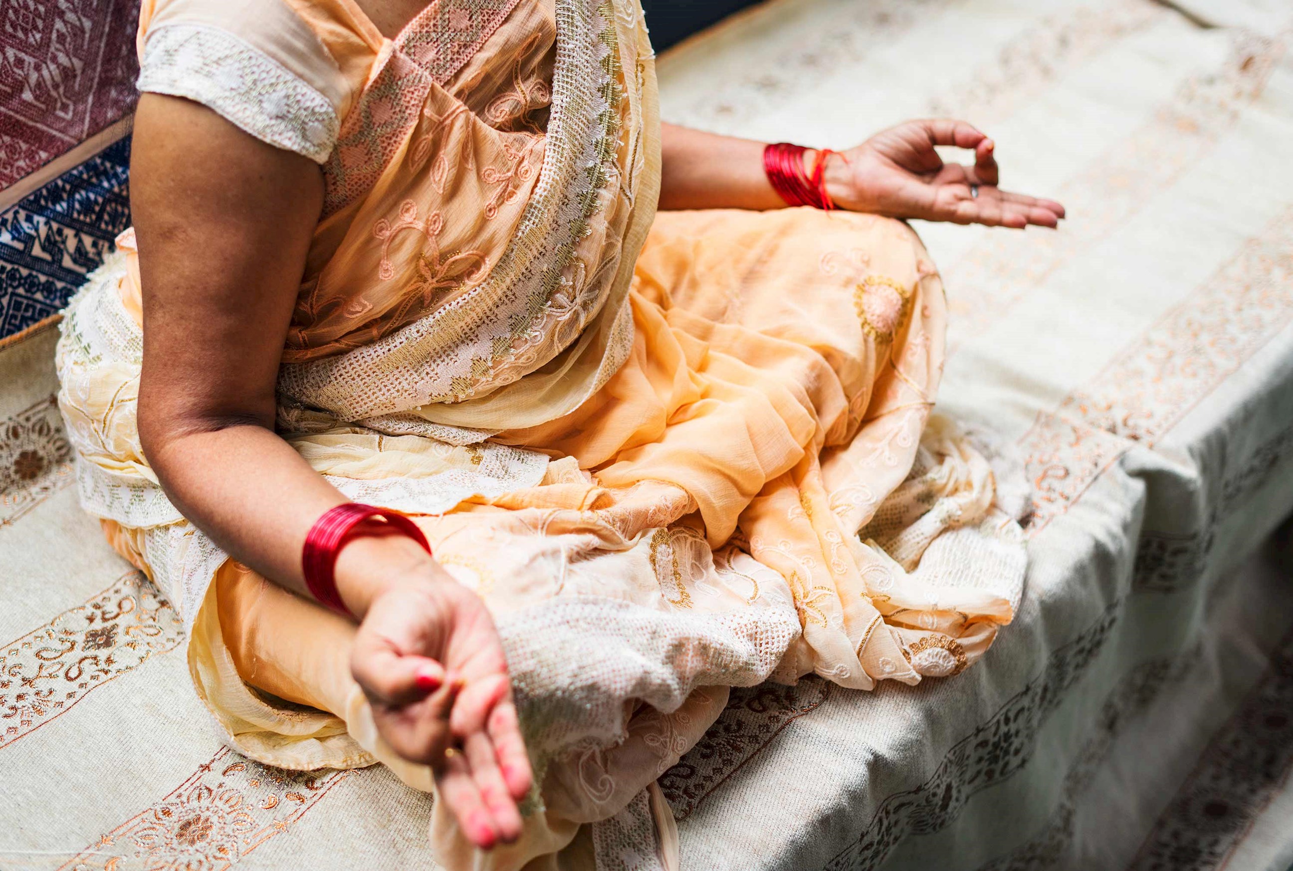 Woman in sari seated lotus style with hands forming Om gesture, Kumarakom, India