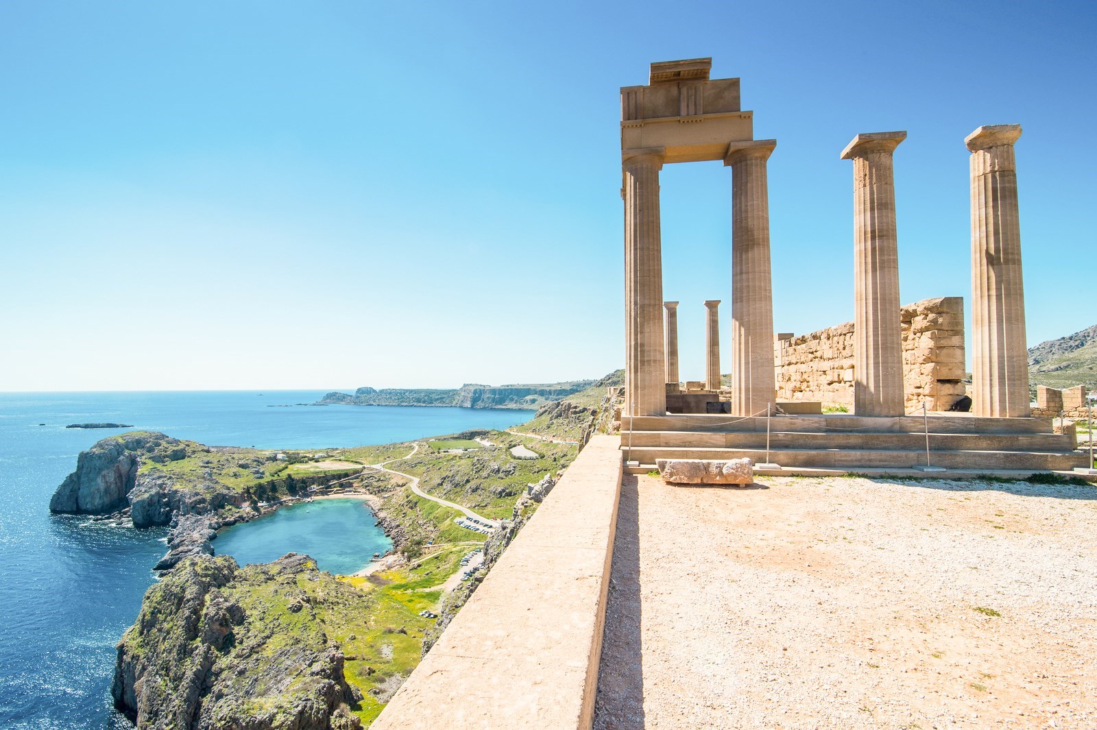 Ancient stone columns of the Acropolis Lindos overlooking blue sea and cliffs, Rhodes, Greece